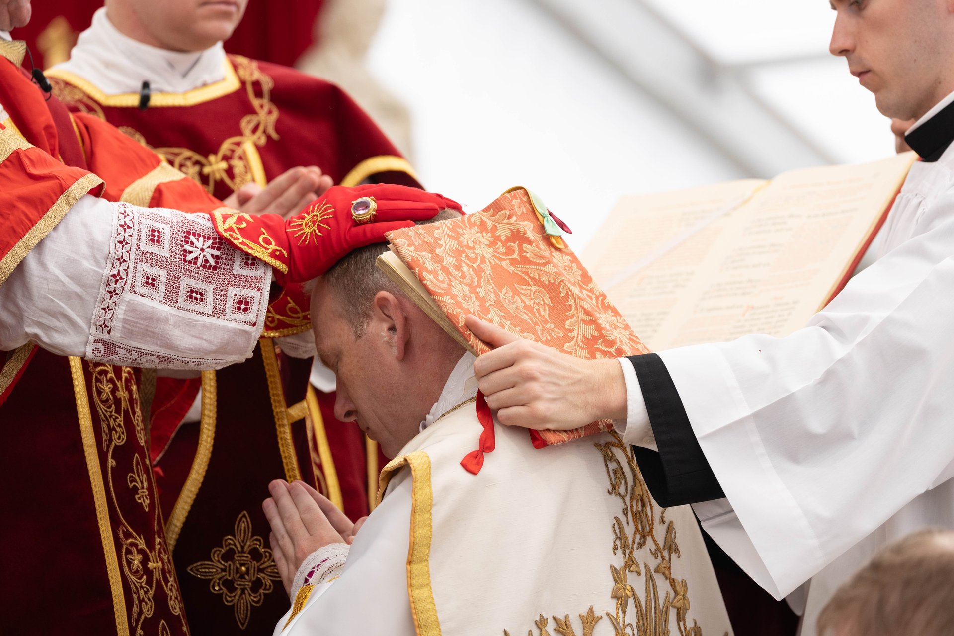 A bishop lays hands on the candidate as …